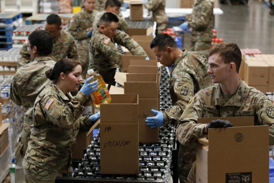 Members of 115th Regional Support Group of the California National Guard load boxes with food at the Sacramento Food Bank and Family Services in Sacramento, Calif., Saturday, March 21, 2020. 