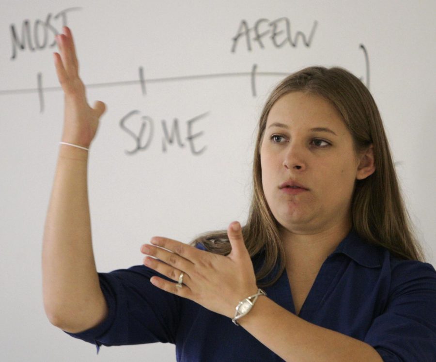 A high school teacher gives instruction to her class in sign.