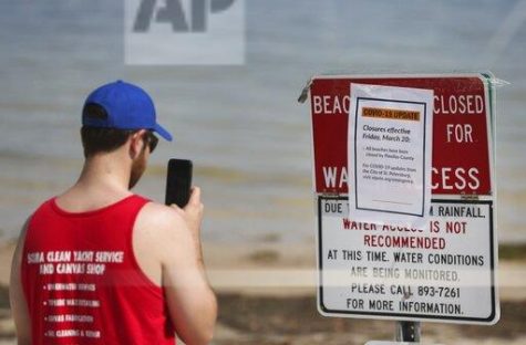 Zac Giparas, 28, takes a picture of the Covid-19 update beach closure sign along the sand at North Shore Park on March 20, 2020 in St. Petersburg. Giparas is a USF grad student currently on spring break. 