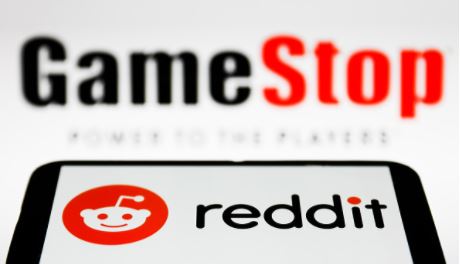 Reddit logo displayed on a phone screen and GameStop logo in the background are seen in this illustration photo taken in Poland on February 1, 2021.