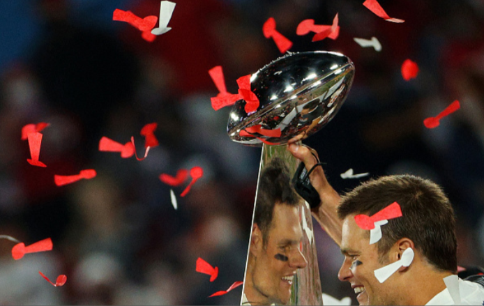 Photo courtesy of Patrick Smith/Getty Images. Tom Brady #12 of the Tampa Bay Buccaneers celebrates as he is reflected in the Lombardi Trophy after defeating the Kansas City Chiefs in Super Bowl LV at Raymond James Stadium on February 07, 2021 in Tampa, Florida. 