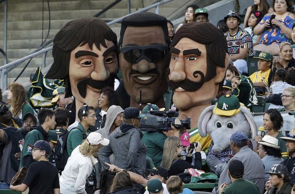 Photo courtesy of AP Images. Contestants dressed as former Oakland Athletics players Dennis Eckersley, left, Rickey Henderson, center, and Rollie Fingers stand with fans after racing during the seventh inning of a baseball game between the Athletics and the Seattle Mariners in Oakland, Calif., July 3, 2015. 