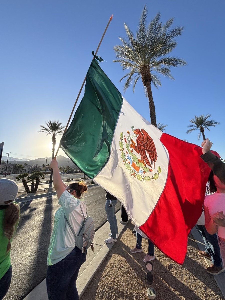 Photo courtesy of The Chaparral/Layla Freiberg. A protestor in Cathedral City waves a Mexican flag. 