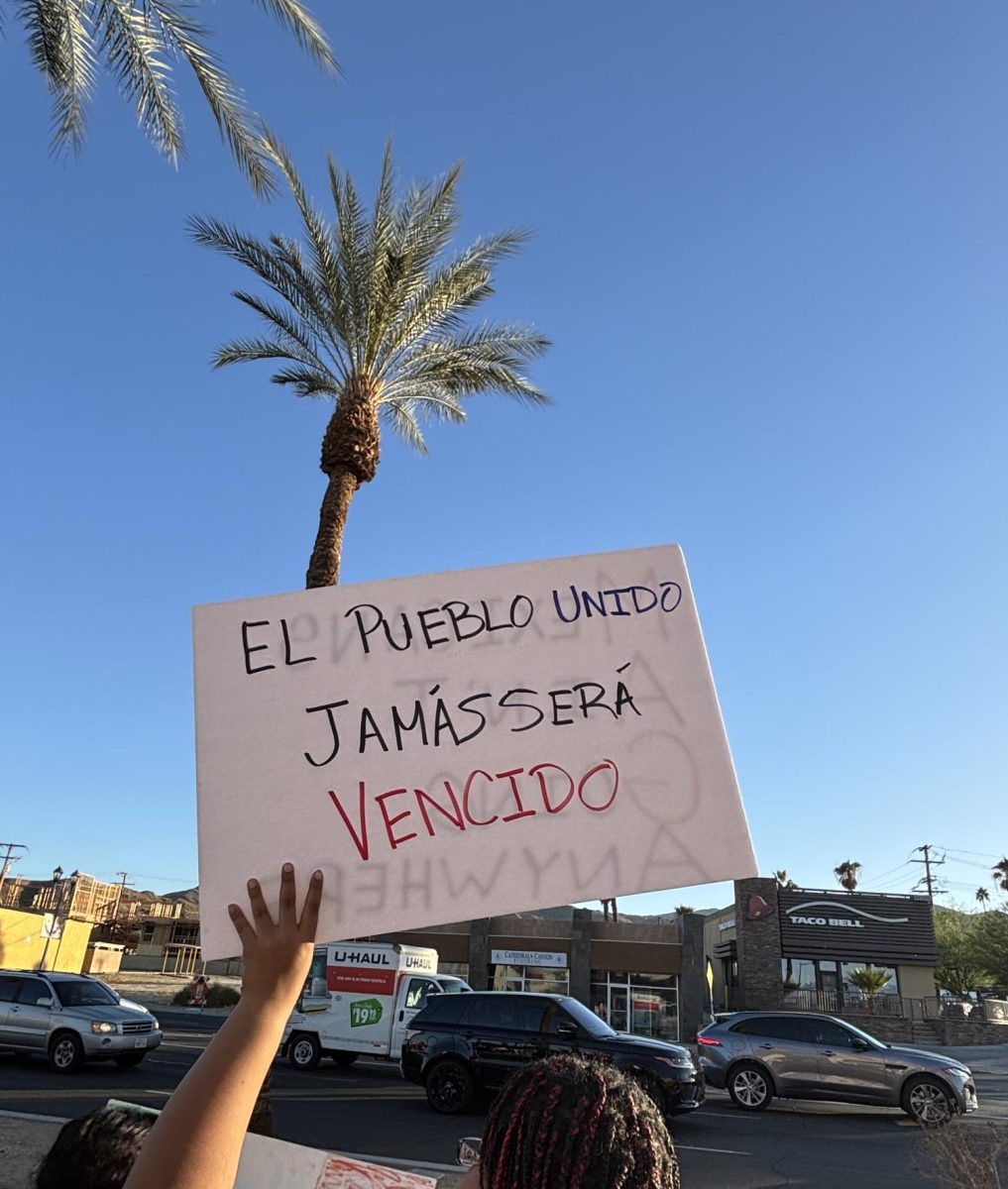 Photo courtesy of The Chaparral/Layla Freiberg. A protestor in Cathedral City holds a sign that reads "El pueblo unido jamás será vencido." 