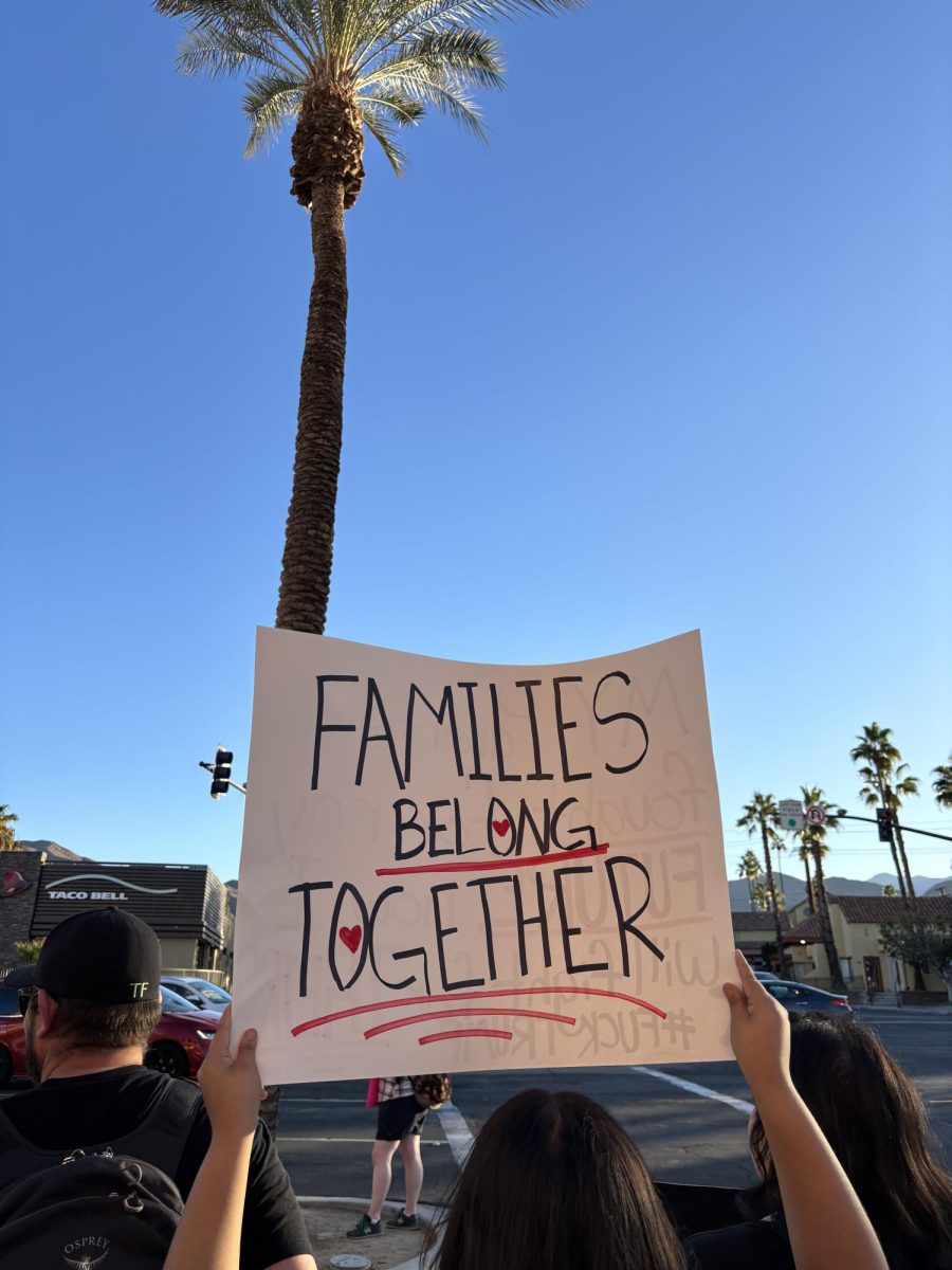 Photo courtesy of The Chaparral/Layla Freiberg. A protestor in Cathedral City holds a sign that reads "Families belong together." 