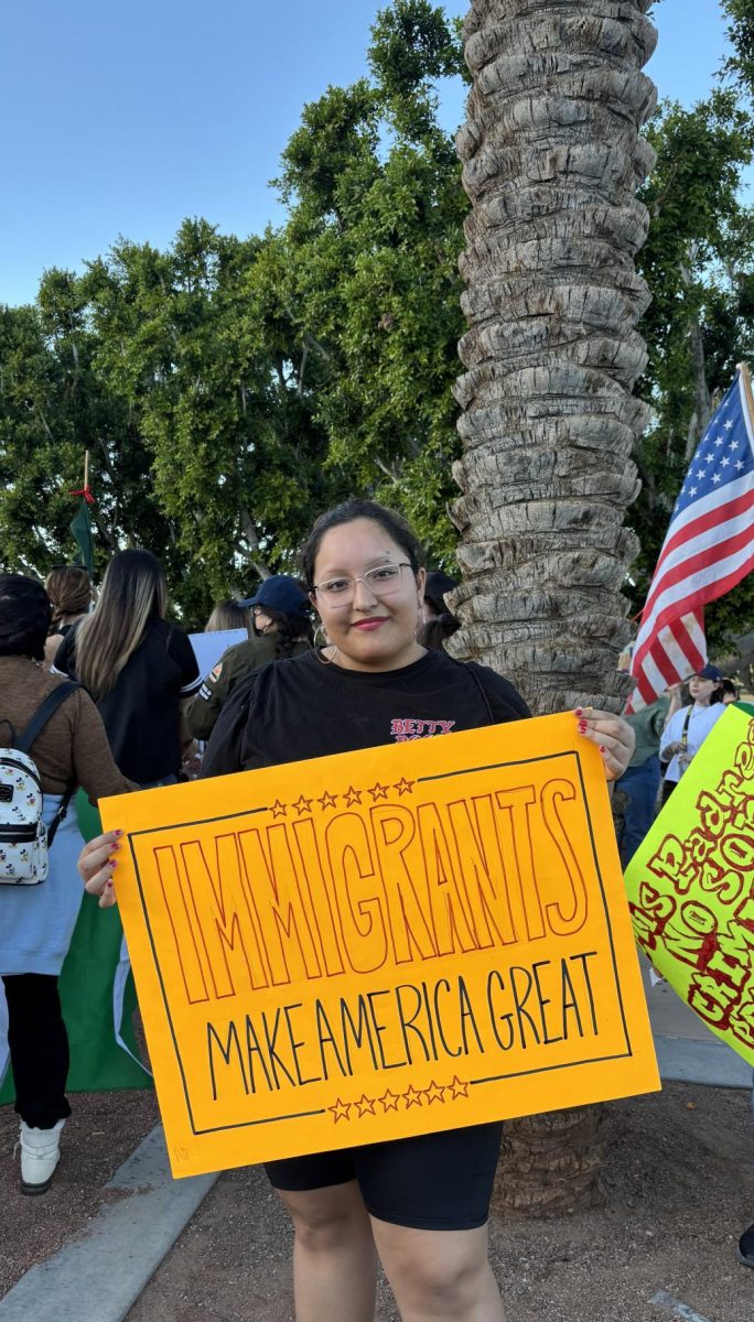 Photo courtesy of The Chaparral/Layla Freiberg. Victoria Randon Santiago holds up her sign that reads "Immigrants make America great," a play on Donald Trump's campaign slogan, "Make America Great Again."