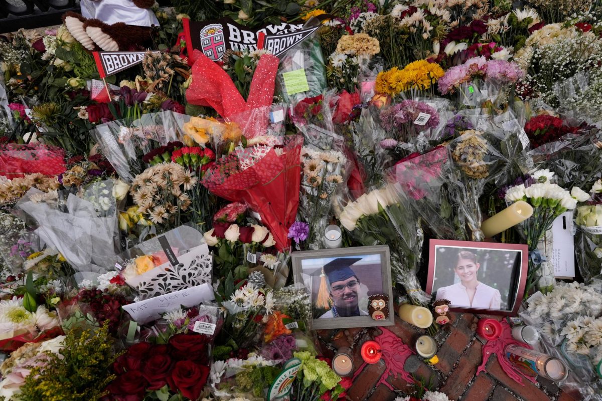 Photos of Brown University shooting victims Mukhammad Aziz Umurzokov, left, and Ella Cook, are seen amongst flowers at a makeshift memorial at the school's Van Wickle Gate, Wednesday, Dec. 17, 2025, in Providence, R.I.
Photo courtesy of AP/ Robert F. Bukaty