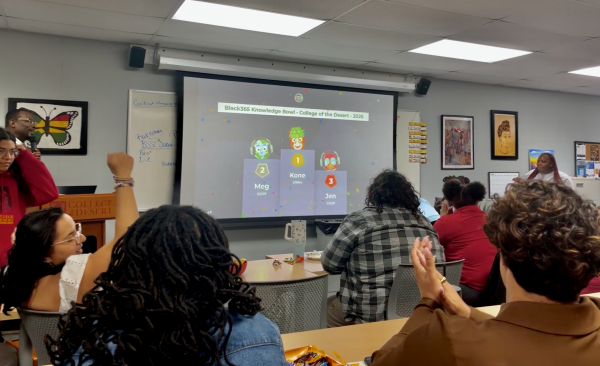 Students cheer as a projector screen reveals the top three winners of a quiz in a podium format. Text at the top of the screen reads "Black365 Knowledge Bowl - College of the Desert - 2026"