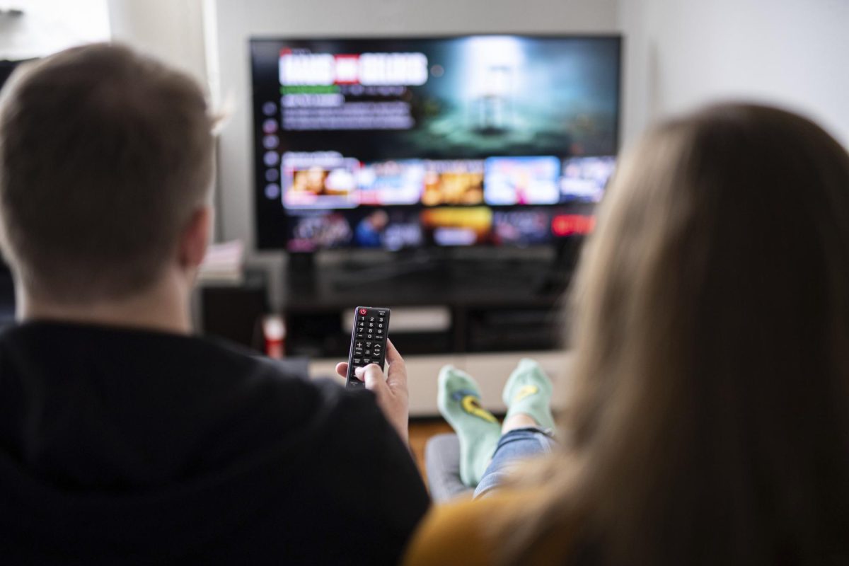 Photo courtesy of Daniel Reinhardt/picture-alliance/dpa/AP Images. A couple sits in front of the television, the man holds the remote control. 